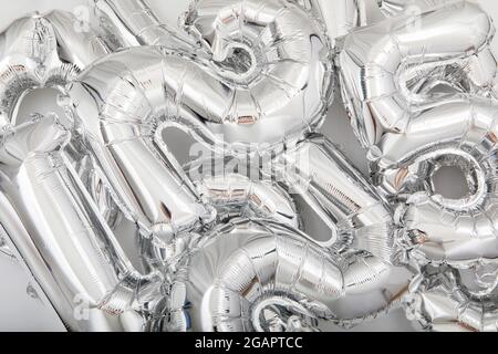 From above of full frame background of various silver number balloons scattered on white table Stock Photo