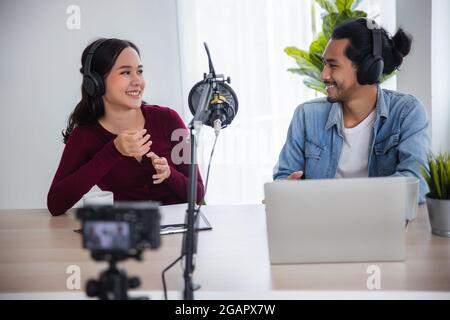 Asian female and male podcaster making audio podcast in home studio, DJ and radio online concept Stock Photo