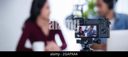 Close up camera recording Asian female and male podcaster making audio podcast in home studio, DJ and radio online concept Stock Photo