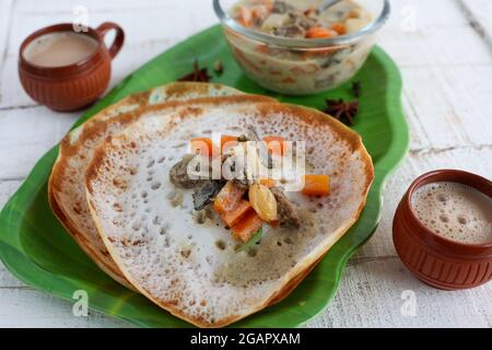 Appam, Hoppers and mutton stew Kerala breakfast food and Indian milk tea chai, christian breakfast India Sri Lanka Tamil Nadu fermented rice pan cake. Stock Photo