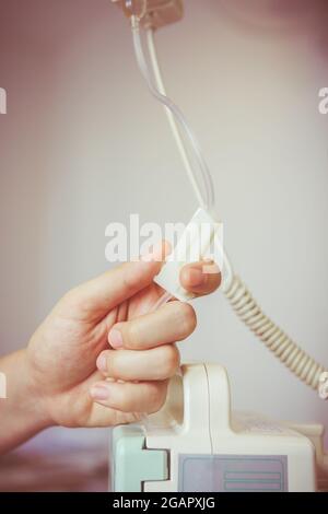 Nurse's hands regulation an intravenous (IV) drip in hospital room. Health care under medical observation. Vignette and vintage picture style. Stock Photo