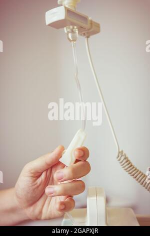 Nurse's hands regulation an intravenous (IV) drip in hospital room. Health care under medical observation. Vignette and vintage picture style. Stock Photo