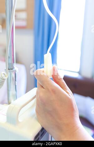 Nurse's hands regulation an intravenous (IV) drip in hospital room. Health care under medical observation. Stock Photo