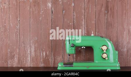 Household appliances - Banner Front view old retro green sewing machine wooden background Stock Photo