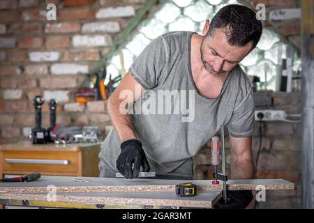 Carpenter doing wood work using clamping hand tool in his workshop ...