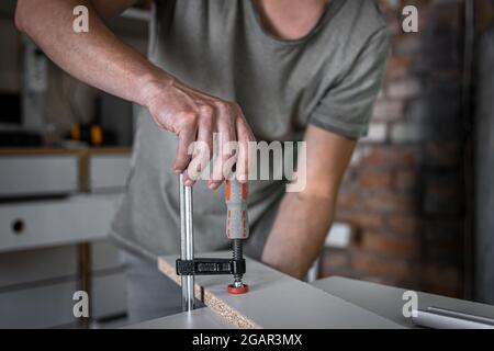 Carpenter doing wood work using clamping hand tool in his workshop. Stock Photo