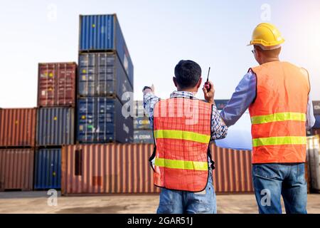 Engineer and architect team check on blueprint  and control by radio working building in warehouse location, container management and cargo export pla Stock Photo
