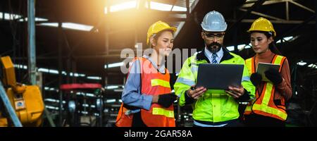 Mechanical engineer manager working in industry and factory control worker and introduce teamwork on laptop wearing safety reflective vest and  helmet Stock Photo