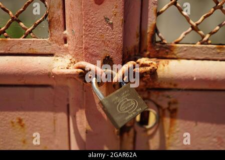 SETUBAL, PORTUGAL - Jul 04, 2021: A closeup shot of a lock on a red worngate Stock Photo