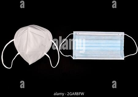 Disposable KN-95 mask vs thin surgical mask. COVID-19 prevention. H1N1, H5N1 safety measures. Isolated on black background. Stock Photo