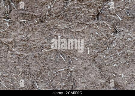 Old clay and straw wall of clay and wood huts of a mazanka, mud hut close up. Mud background. Stock Photo