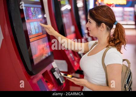 Caucasian woman buying cinema ticket at self-service box office. Stock Photo