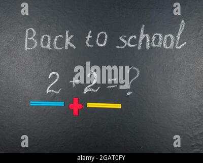 Multicolored colorful numbers, counting sticks, math signs on a chalkboard. Back to school. Concepts. School supplies on a chalkboard. View from above Stock Photo