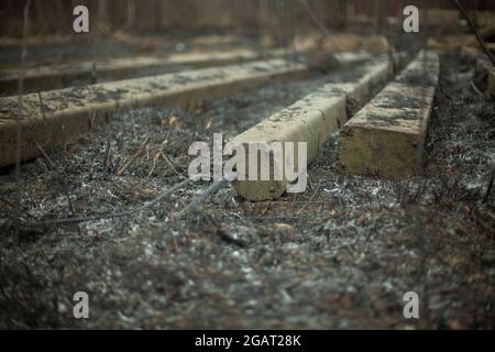 Concrete beams on the ground. Build materials after a fire. Remains on the scorched earth. Concrete blocks. Stock Photo