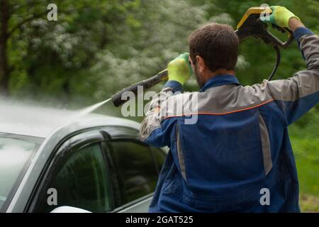 The car is washed at the car wash. Washing the car from dirt. High pressure water spraying equipment for washing car surfaces. Stock Photo