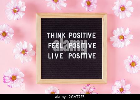 Think positive, feel positive, live positive. Motivational quote on letter board and flowers on pink background. Concept inspirational quote of the da Stock Photo