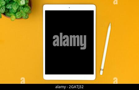 Top view workspace on yellow desktop with tablet and stylus pencil, copy space Stock Photo