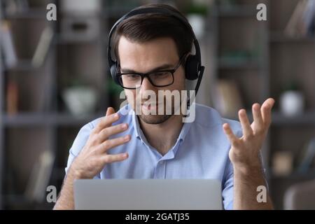 Young male in headphones speak by videocall on pc Stock Photo