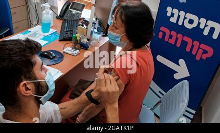 A health worker administers a third dose of the Pfizer-BioNtech COVID-19 vaccine to an Israeli woman on August 01, 2021 in Jerusalem, Israel. Israel started administering a third dose of the Pfizer Covid-19 vaccine to people over 60 due to concern about the more virulent Delta variant, making Israel the first country in the world to do so. Stock Photo