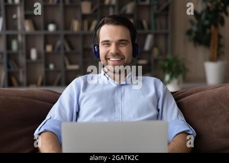 Young guy in headset look at camera above pc screen Stock Photo