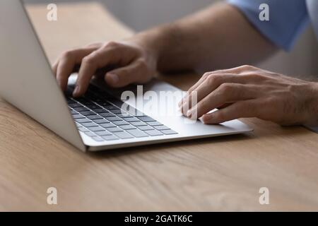 Closeup of millennial male hands typing on modern laptop keyboard Stock Photo