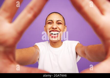 Portrait of a cheerful female with hands in front. Woman with shaved head looking at camera and smiling. Stock Photo