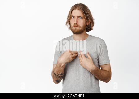 Image of confused, surprised blond man pointing at himself with startled face, cant understand why me him, standing over white background Stock Photo