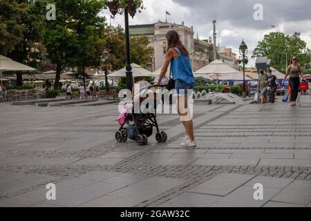 Serbia, Jul 3, 2021: Young woman pushing baby stroller down the Republic Square in Belgrade Stock Photo