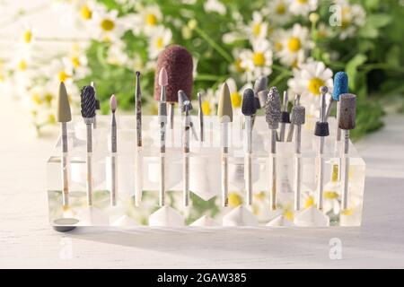 grinding and polishing attachments for cosmetic treatments such as manicure and pedicure in a transparent holder, blurry flowers in the background, se Stock Photo