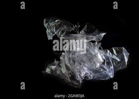 plastic foil from a disposable bag shown like a horse sculpture against a black background, packaging waste of abundance and throwaway society, consum Stock Photo