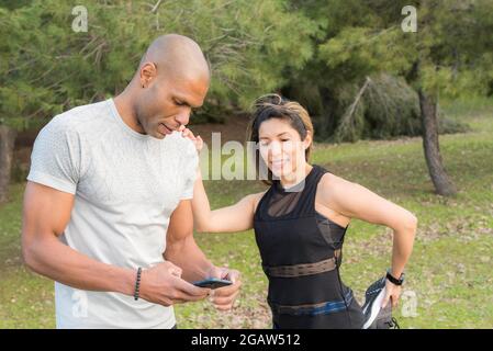 Fitness woman doing stretching leg on her partner who is using cell phone Stock Photo