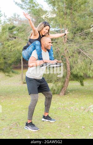 Sportswoman sitting on the shoulders of sportsman exercising and having fun Stock Photo