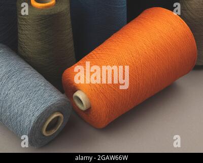 Cones of colored cotton, woolen or synthetic threads. Bobbins of yarn using in textile manufacturing and for handmade products, copy space Stock Photo