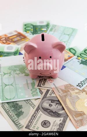 Pig shaped piggy bank, euro banknotes and us dollars on isolated white background Stock Photo