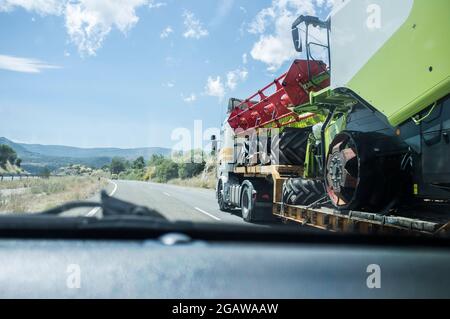 Heavy-duty truck carrying harvester. View from the inside of the car while overtaking Stock Photo