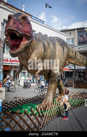 life-size dinosaurs models exhibited at various locations in the city center of Bochum, here: Tyrannosaurus, boy with stuffed animal, North Rhine-West Stock Photo