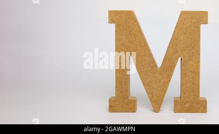 Letter M made of MDF on a white background Stock Photo