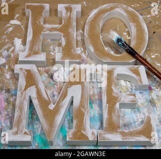 Unfinished and unpainted letters HOME made of MDF on a workshop table Stock Photo