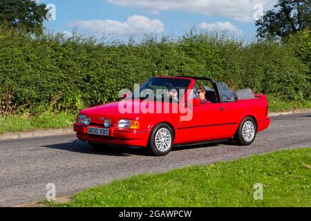 A 1989 80s eighties Ford Escort Xr3i Red Car Cabriolet classic vintage car arriving at the Capesthorne Hall classic car show. Stock Photo