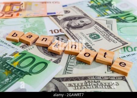 banknote inscription on wooden cubes on the texture of us dollars and euro banknotes Stock Photo