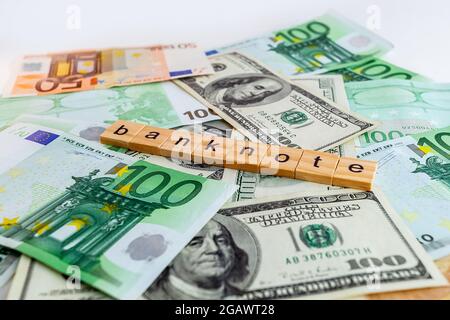 banknote inscription on wooden cubes on the texture of us dollars and euro banknotes Stock Photo