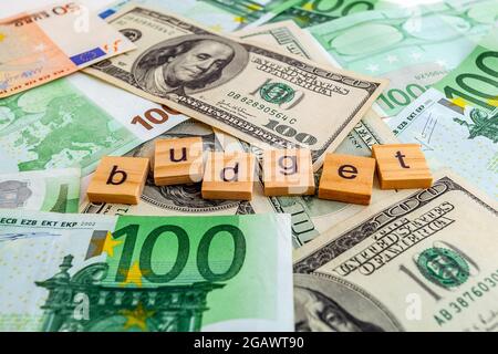 budget inscription on wooden cubes on the texture of us dollars and euro banknotes Stock Photo