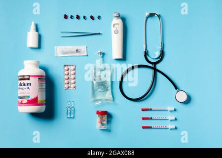 Overhead view of a medical instruments consisting of a jar of calcium, syringes, thermometer, stethoscope, tweezers lying on a blue background in the Stock Photo