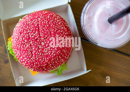Colored pink beetroot gluten-free hamburger bun with vegetarian burger, with pink milkshake. Healthy alternative burger. Trendy food. Top view. Stock Photo