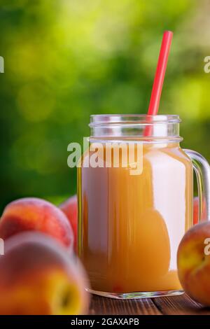 peach juice in glass mason jar with ripe fruits Stock Photo