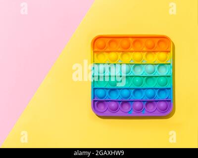Popit on yellow and pink background with copy space. Popular silicone colorful antistress pop it toy for child on pink and yellow background. Top view from above. Simple dimple Stock Photo