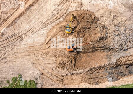 two excavators working at construction site on earthworks. heavy construction machinery. aerial view. Stock Photo
