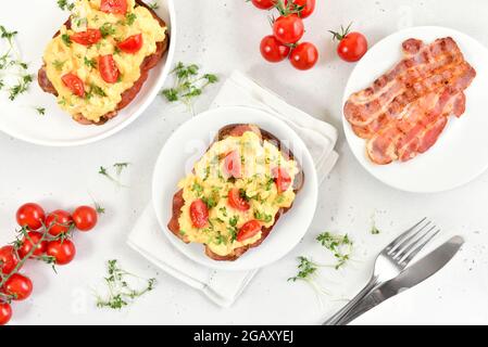 Scrambled eggs with microgreen, bacon and tomatoes on bread. Top view, flat lay Stock Photo