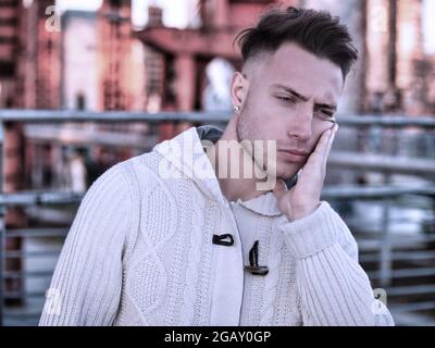 Good looking young man with hand on his face because of tooth-ache Stock Photo