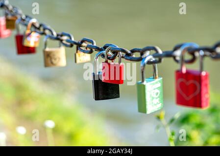 Red padlock suspended on a chain engraved with one heart. Stock Photo